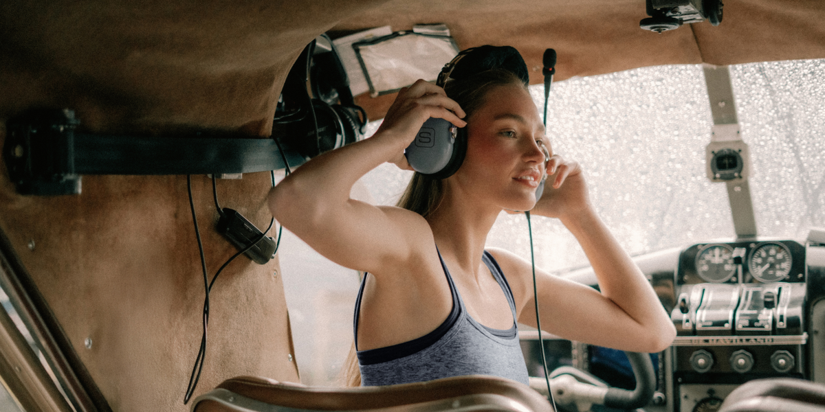 Woman wearing headphones inside a vehicle with a dashboard visible