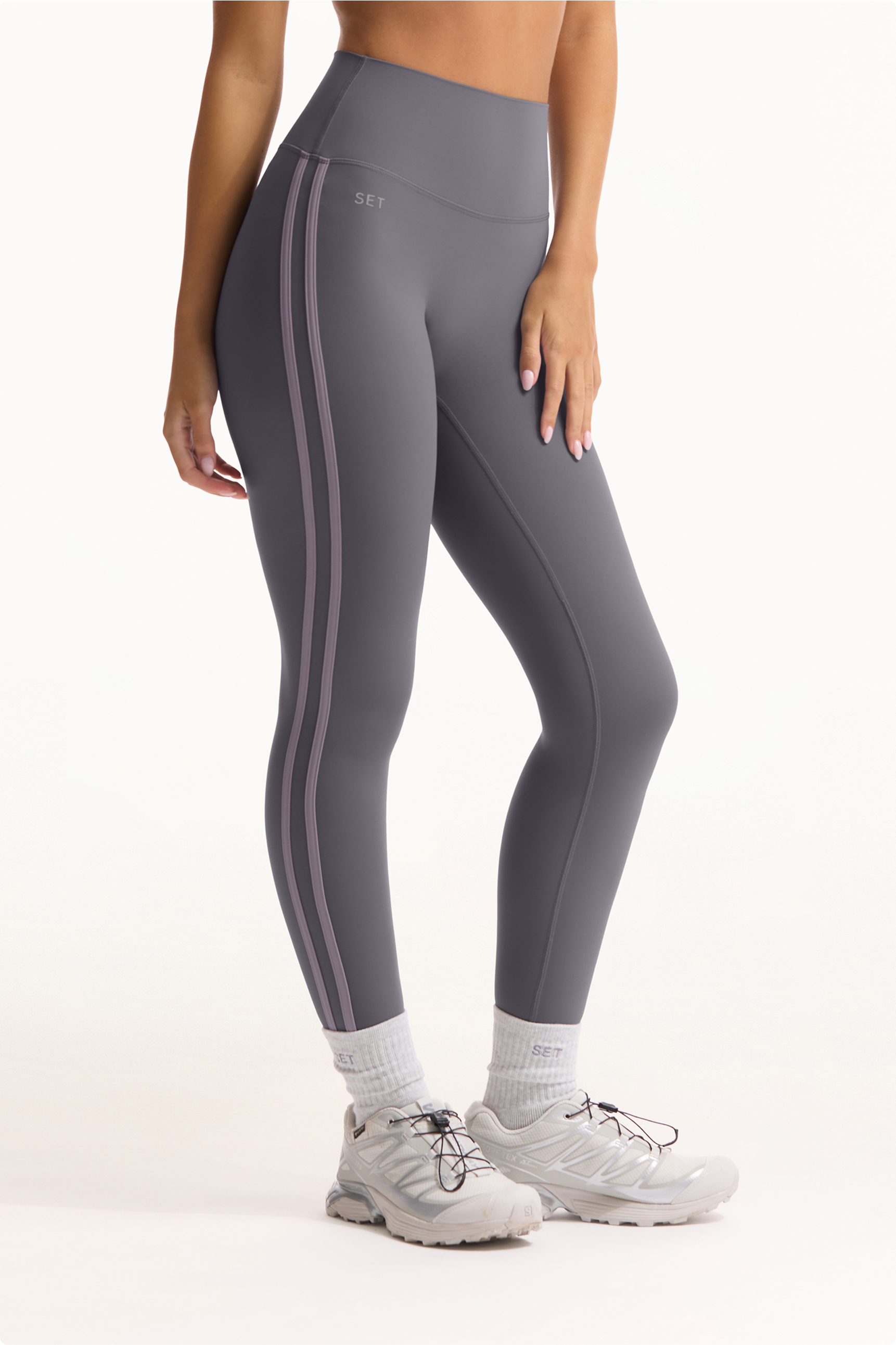 Person wearing gray leggings with white stripes on a white background 