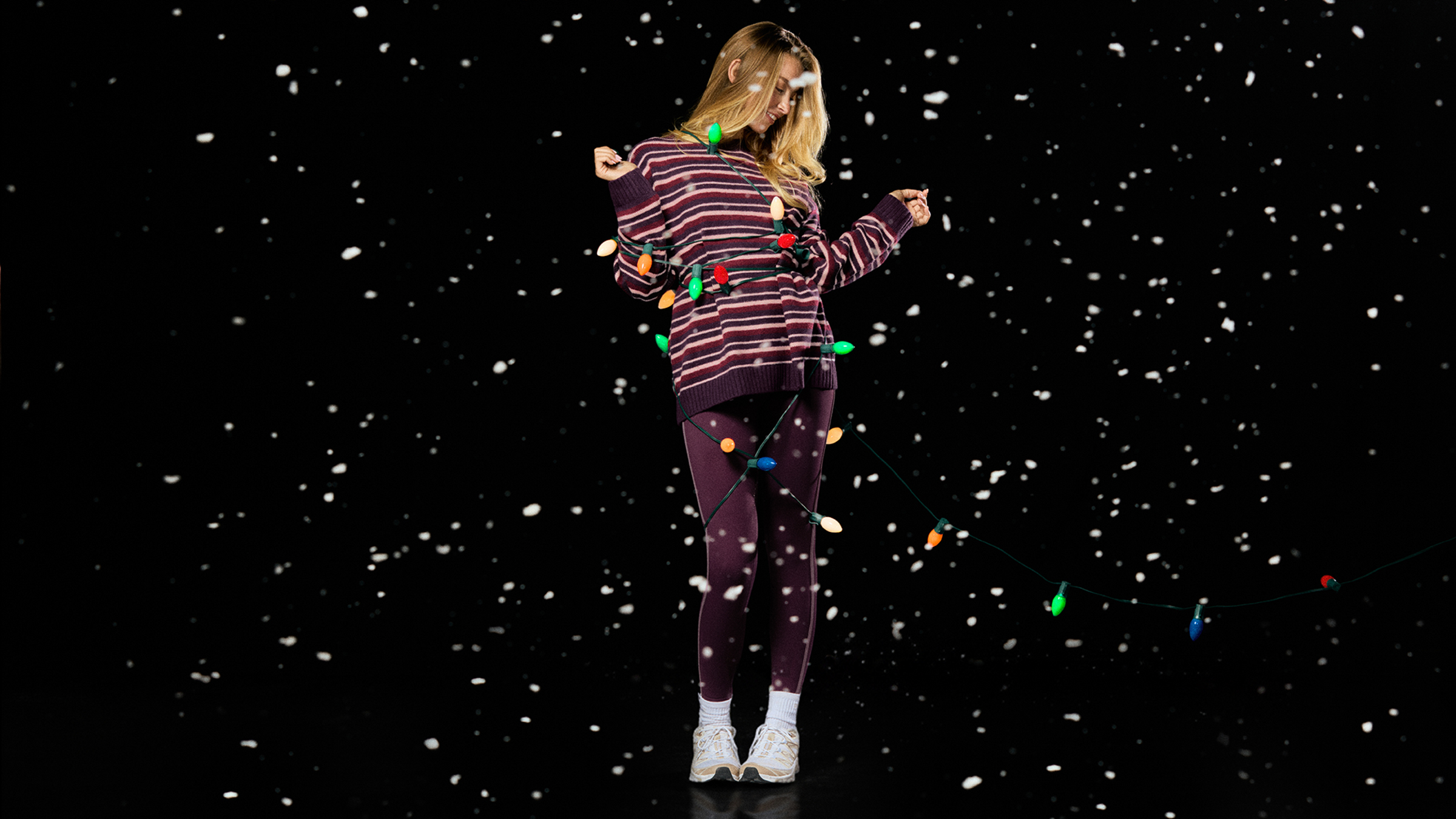 Person wearing a festive outfit with lights against a snowy background