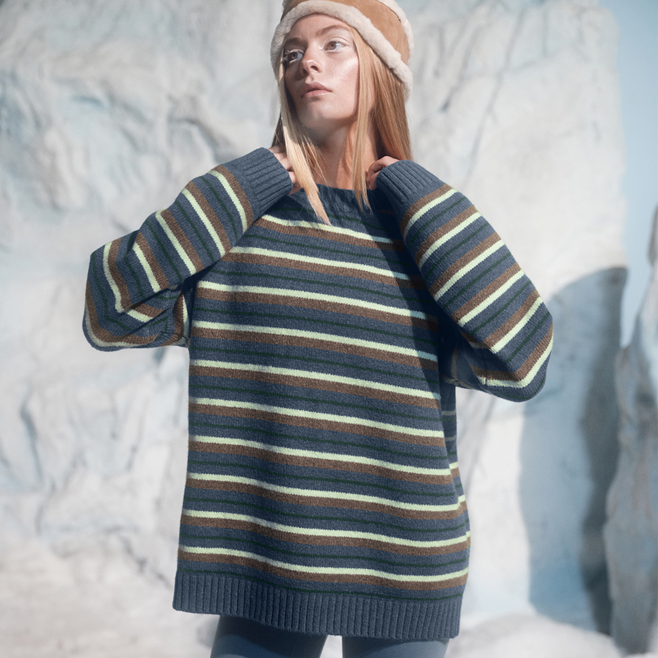 Person wearing a striped sweater and hat in a snowy landscape