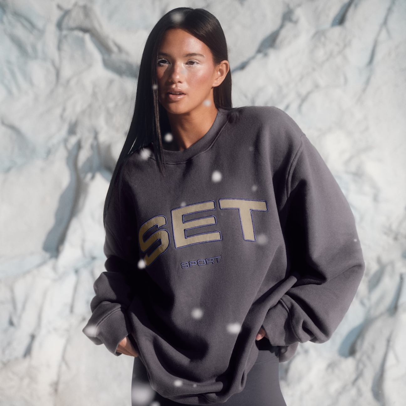 Person wearing a dark gray sweatshirt with 'SET' branding against a snowy background