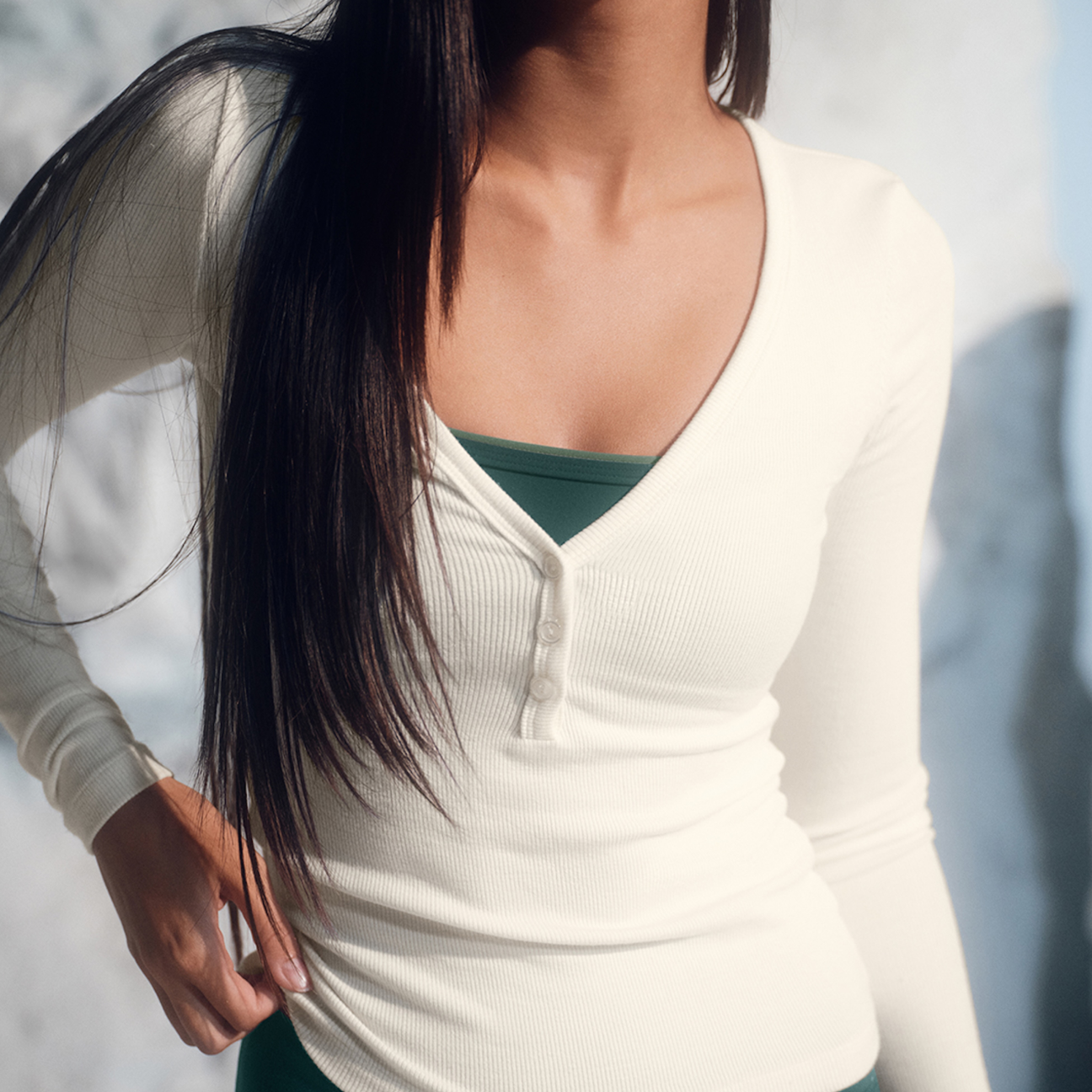 Close-up of a person wearing a white long-sleeve top with a blurred background