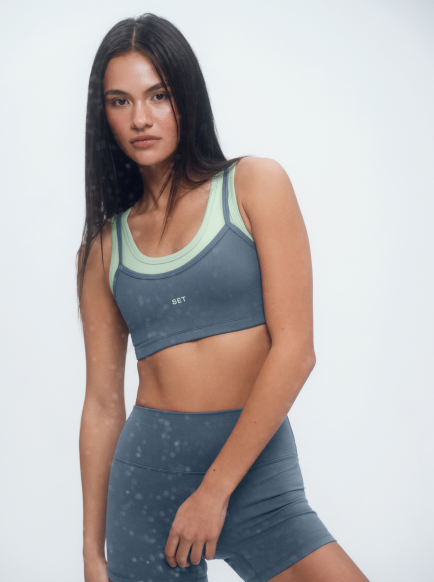 Woman wearing a gray sports bra and shorts set on a white background