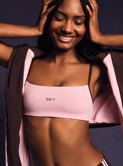 Woman wearing a pink sports bra with 'SET' branding against a dark background