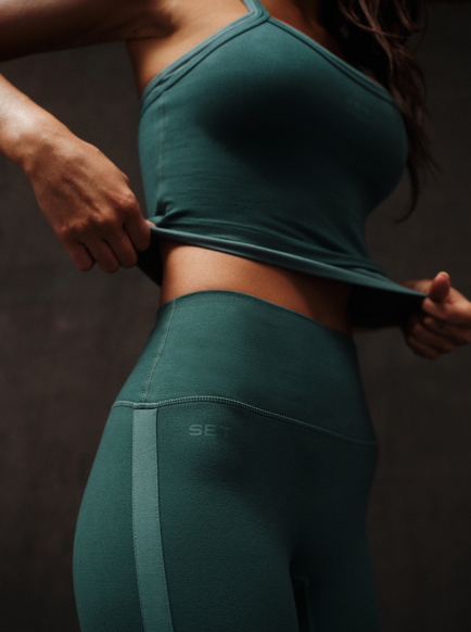 Person wearing a green sports bra and leggings with 'SET' branding on a dark background