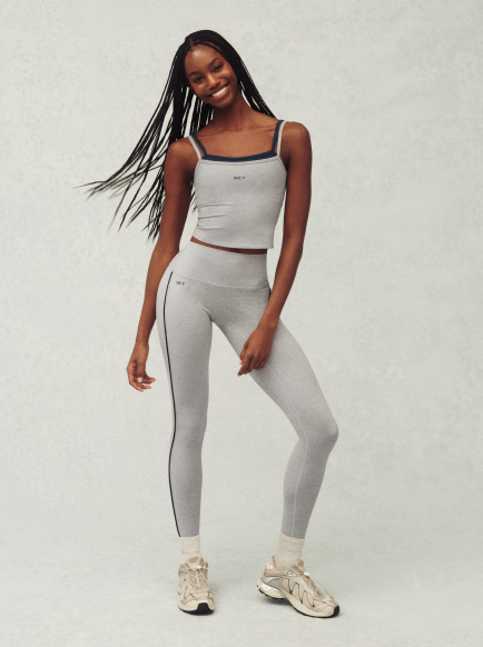 Woman wearing a gray athletic outfit with a white background
