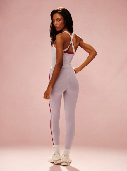 Woman wearing a white and red sports outfit on a pink background