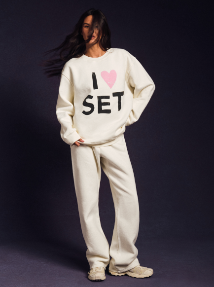 Person wearing a white sweatshirt with 'I ❤️ SET' text on a dark background