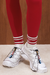 Person wearing red leggings with grey and red striped half crew socks and white athletic shoes.