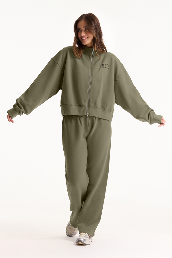 Person wearing a green tracksuit with 'SET' branding on a white background