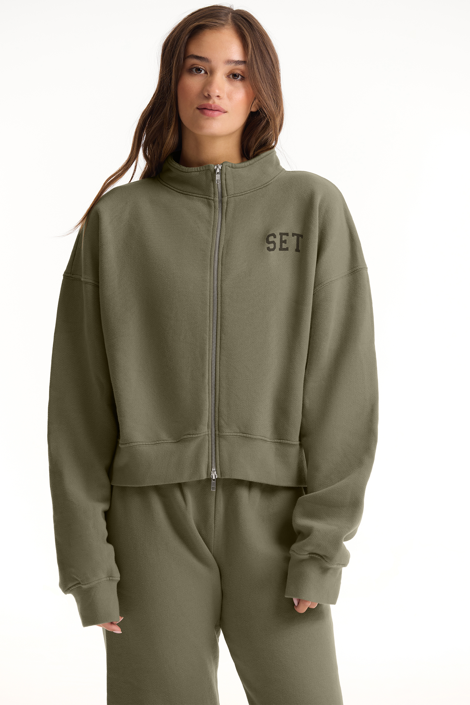 Person wearing a green tracksuit with 'SET' logo on a white background <model-info>Sophie wears a size L and is 5’9½”, 23” waist, 34CD bust.</model-info>