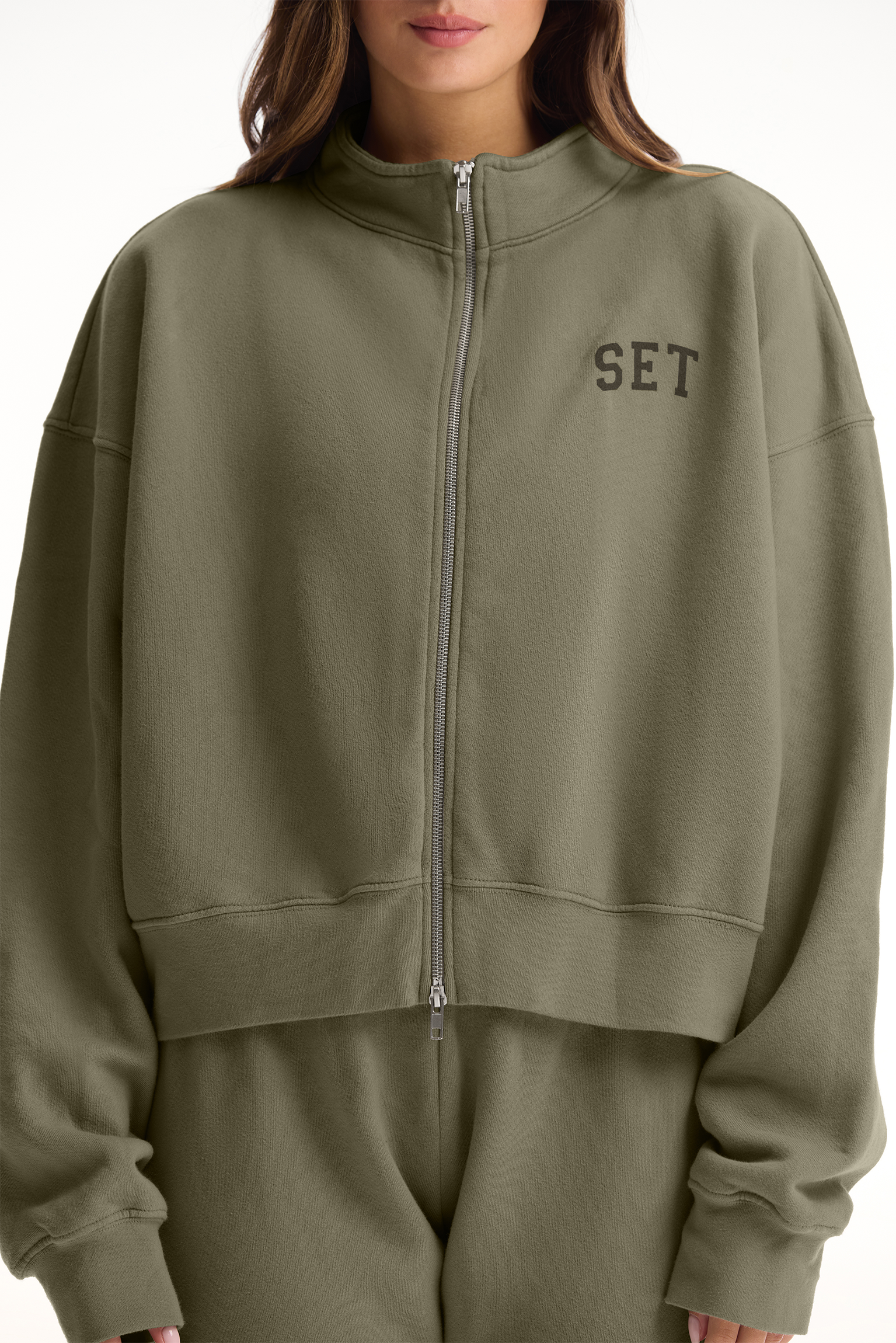 Person wearing a green tracksuit with 'SET' logo on a white background