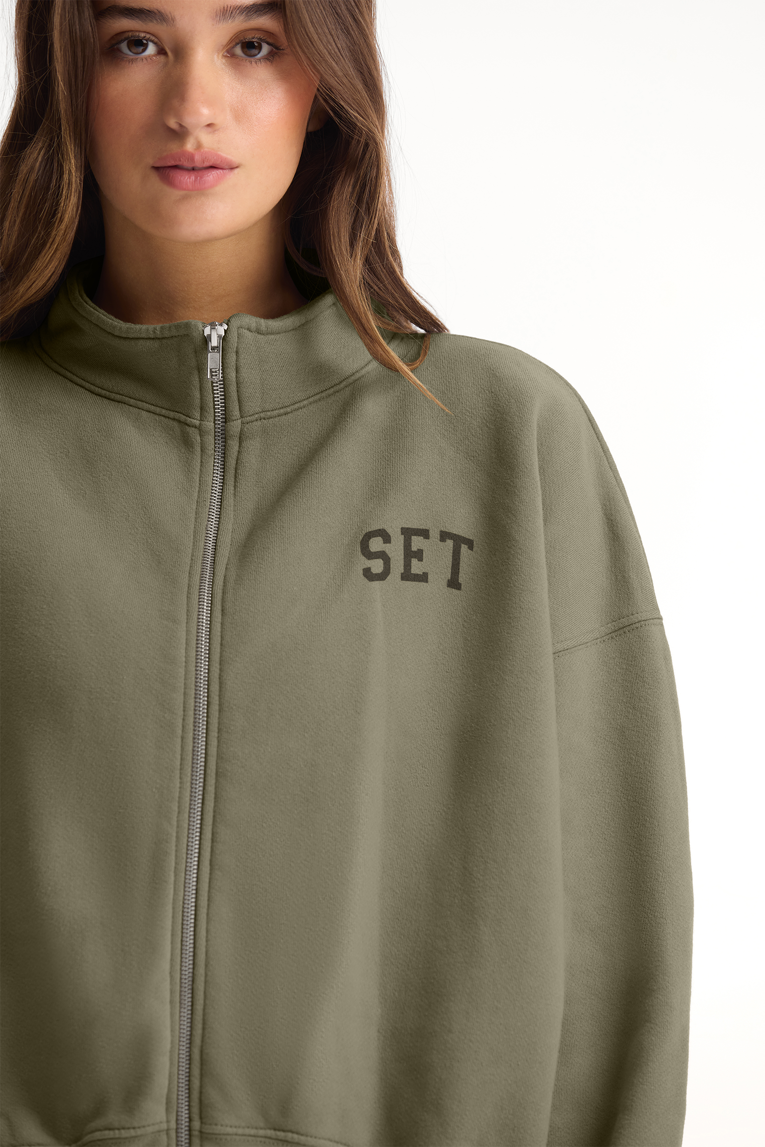 Person wearing a green jacket with 'SET' embroidery on a white background