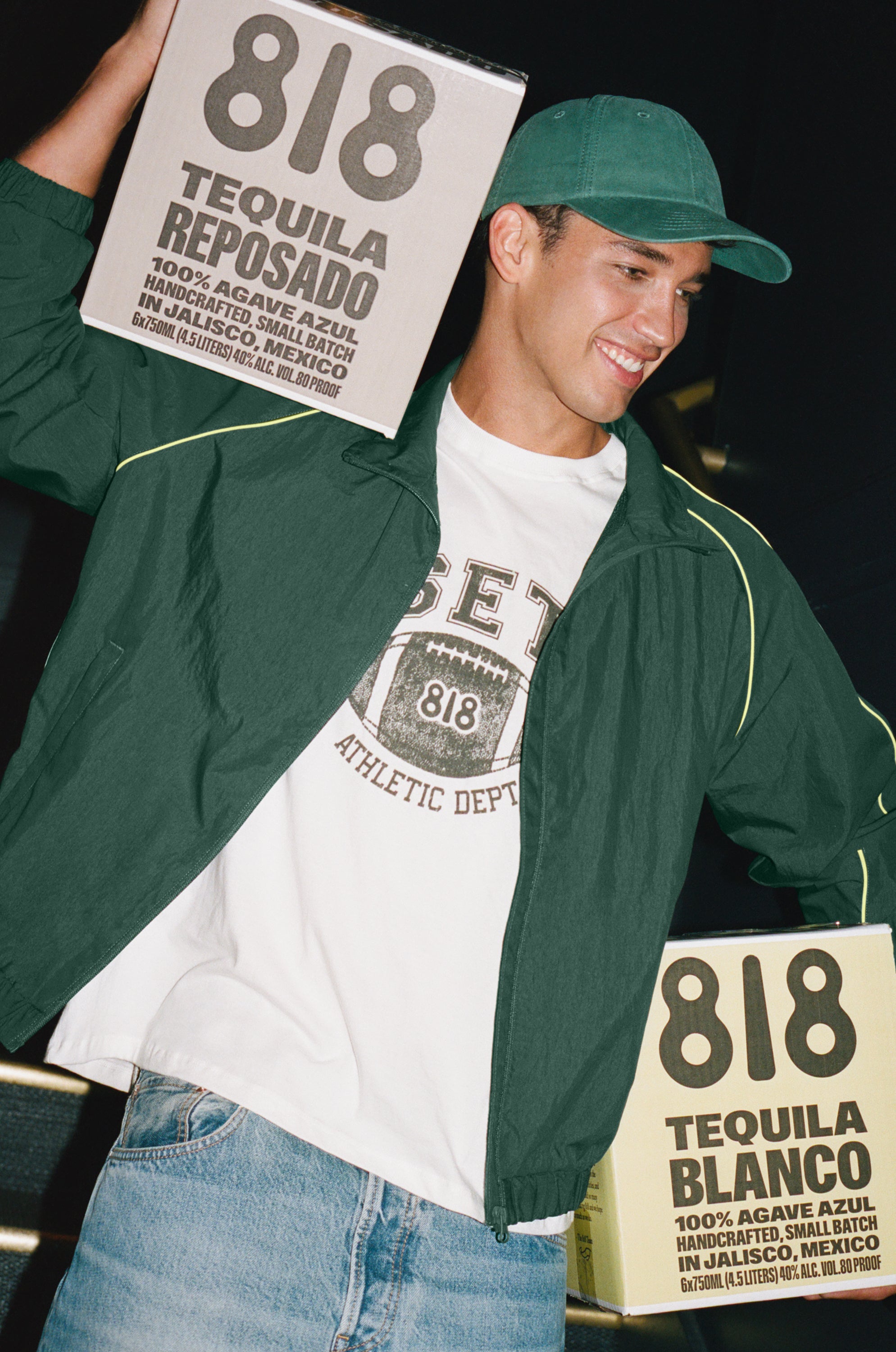 Person wearing a green jacket and white t-shirt with '818' branding, holding 818 Tequila boxes.