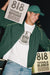 Person wearing a green jacket and white t-shirt with '818' branding, holding 818 Tequila boxes.