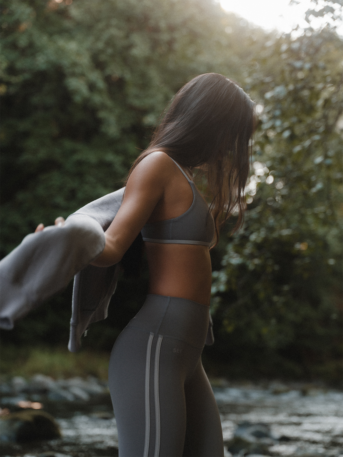 Woman in athletic wear standing outdoors with greenery in the background