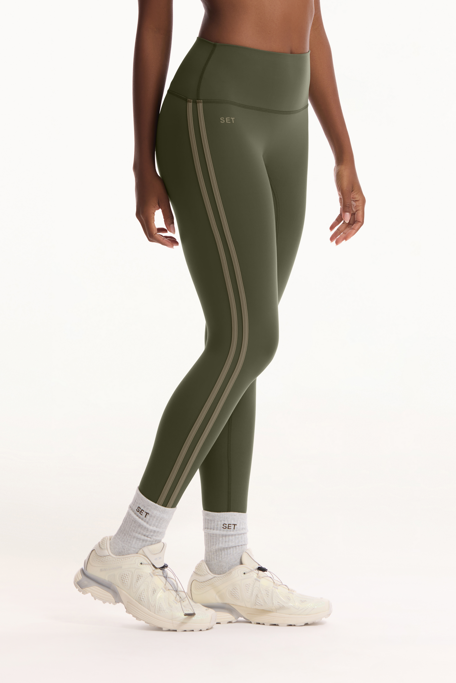 Person wearing green athletic leggings with white stripes on a white background <model-info>Autumn wears a size S and is 5’7½”, 25” waist, 32” bust.</model-info>